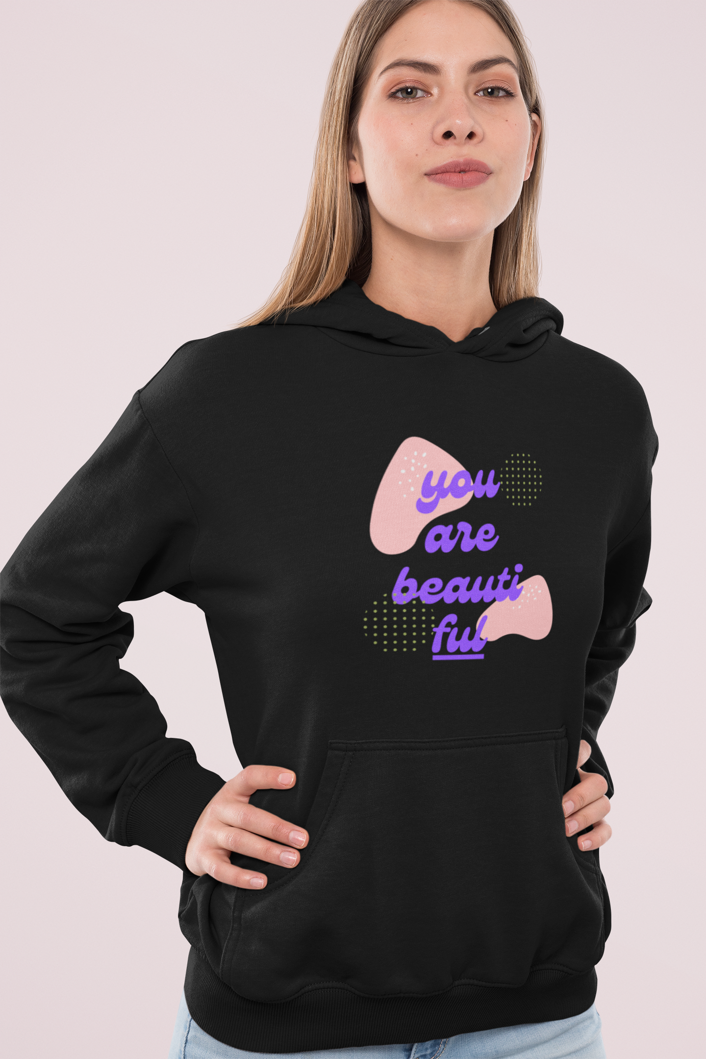 Woman wearing a black hoodie with a motivational quote on a plain background