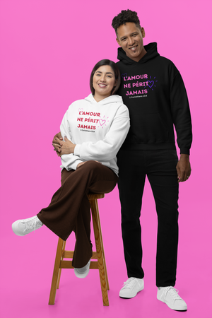 Two people wearing hoodies with French text on a pink background