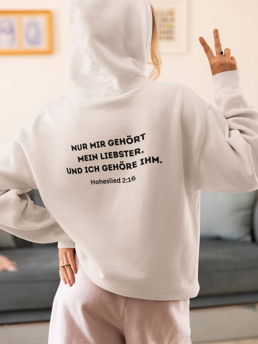 Person wearing a white hoodie with text on the back in a living room setting