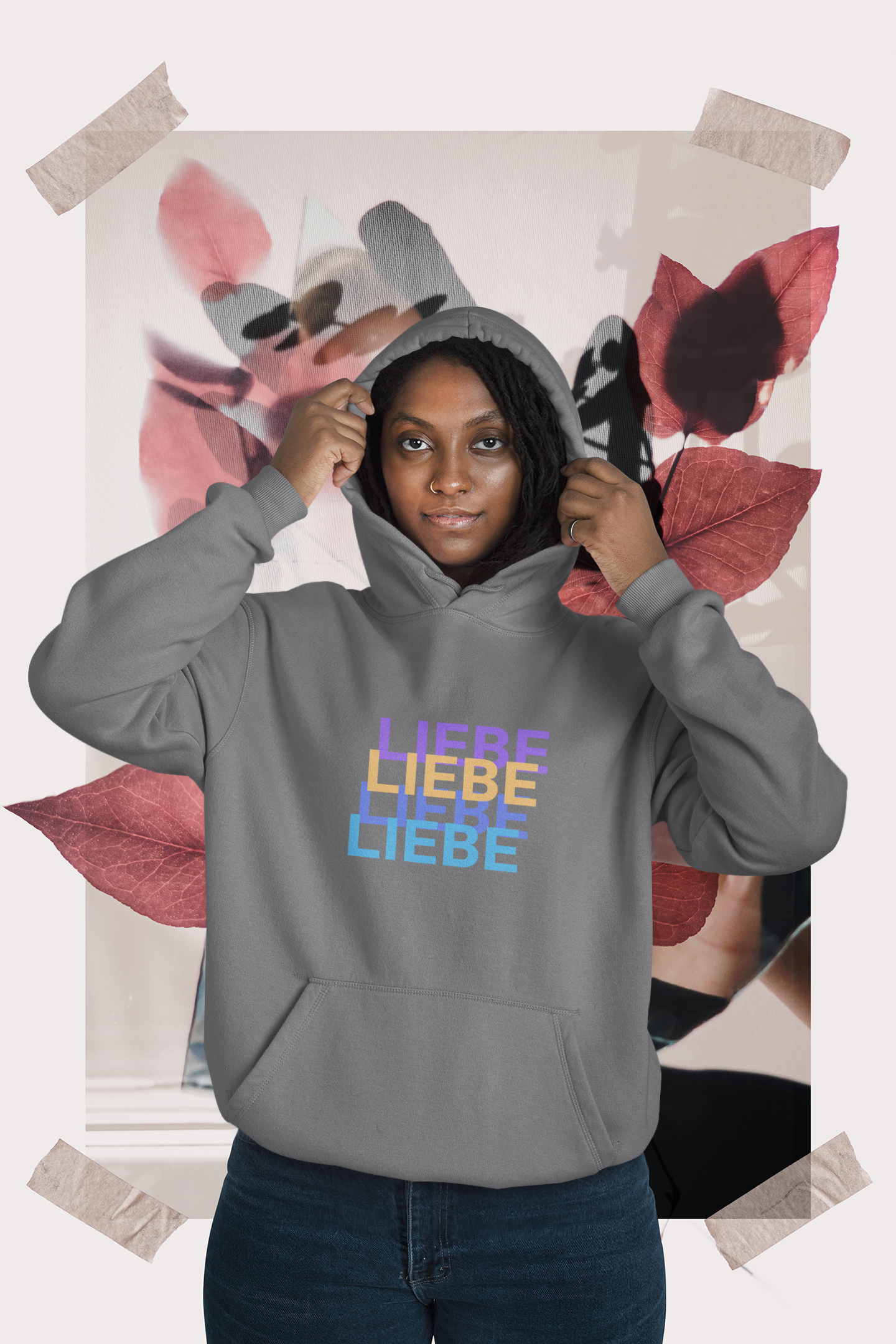 Person wearing a gray hoodie with colorful text in front of a floral background