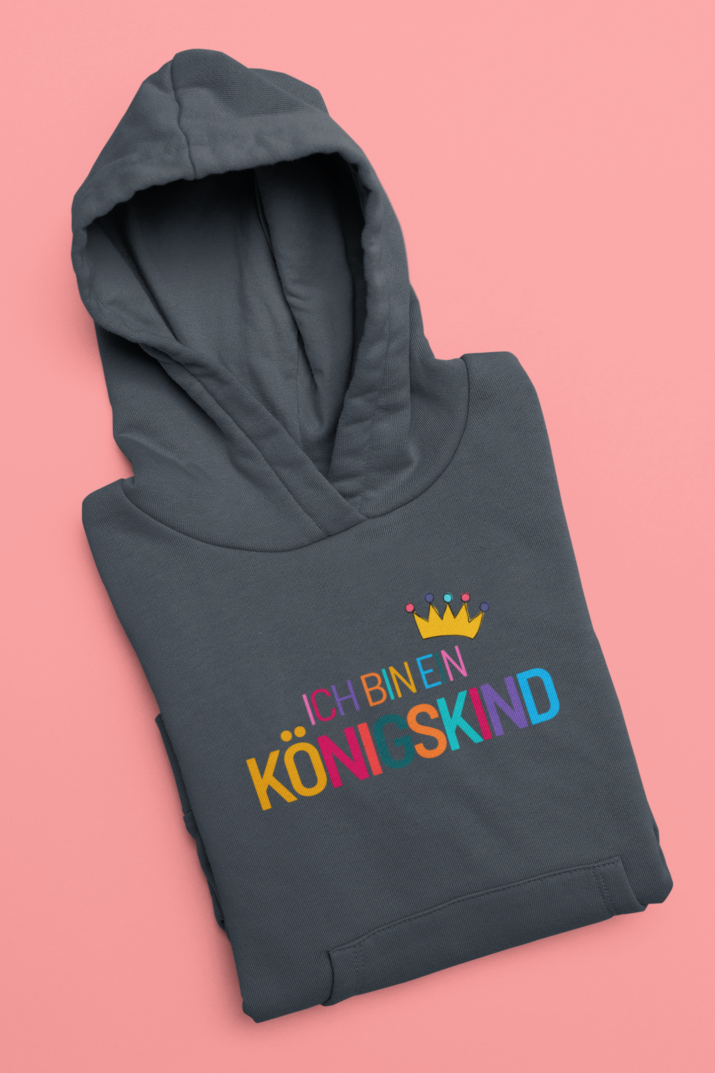 Folded dark gray hoodie with colorful text and a crown on a pink background