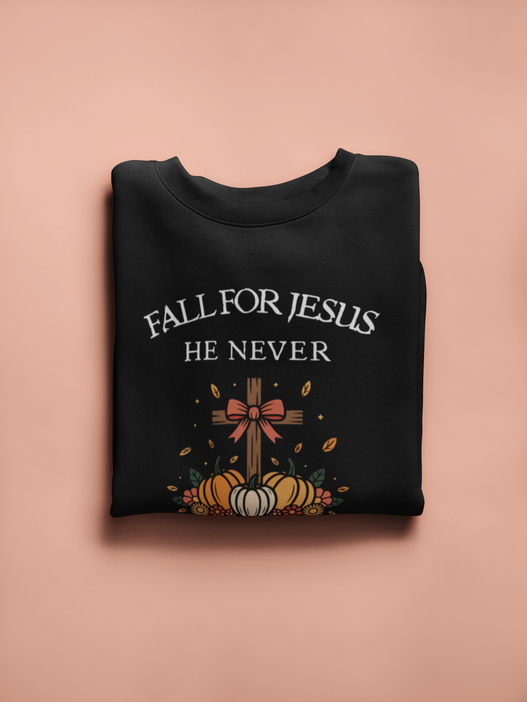 Black sweatshirt with 'Fall for Jesus He Never' text and cross design on a pink background