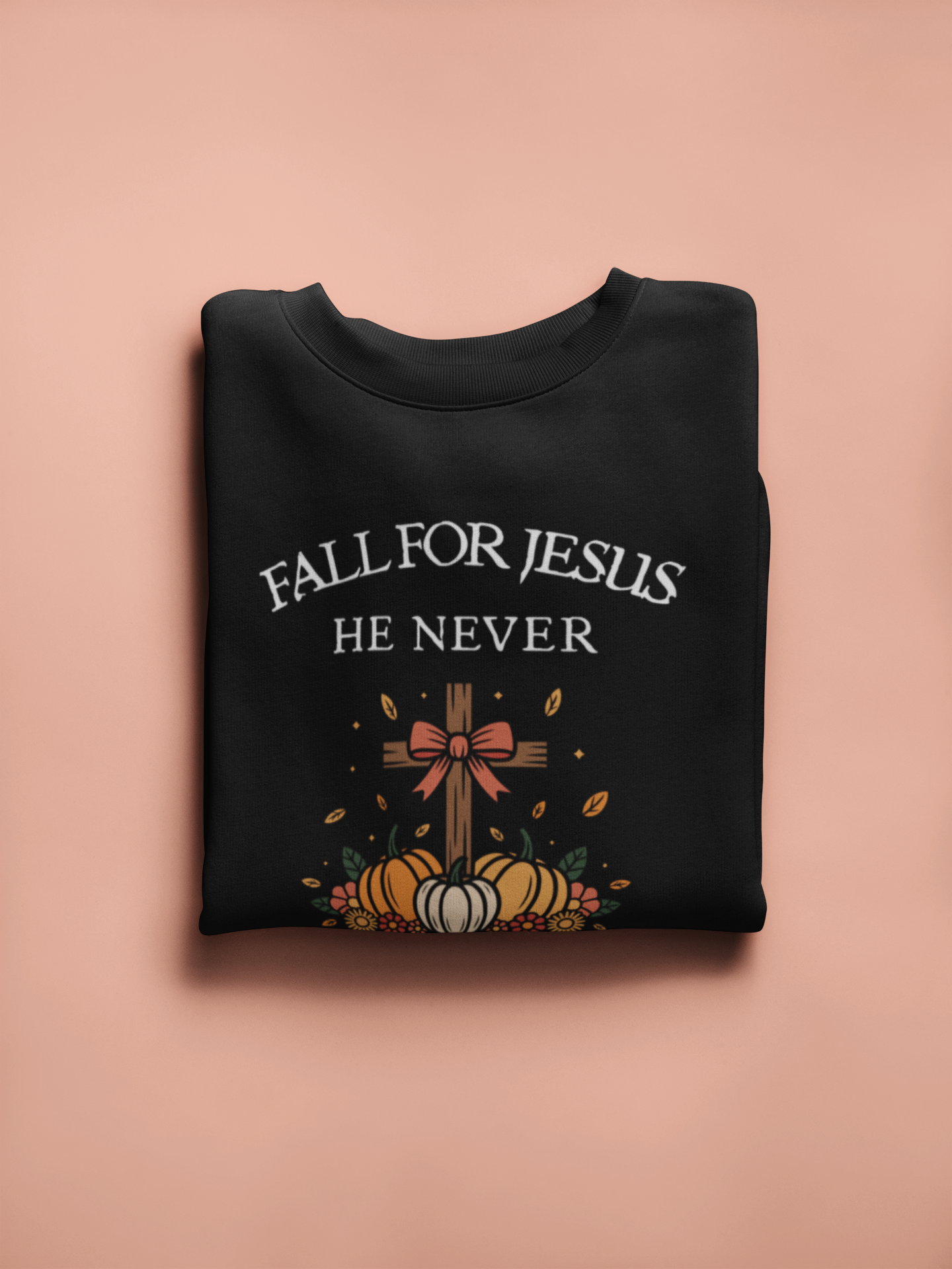 Black sweatshirt with 'Fall for Jesus He Never' text and cross design on a pink background