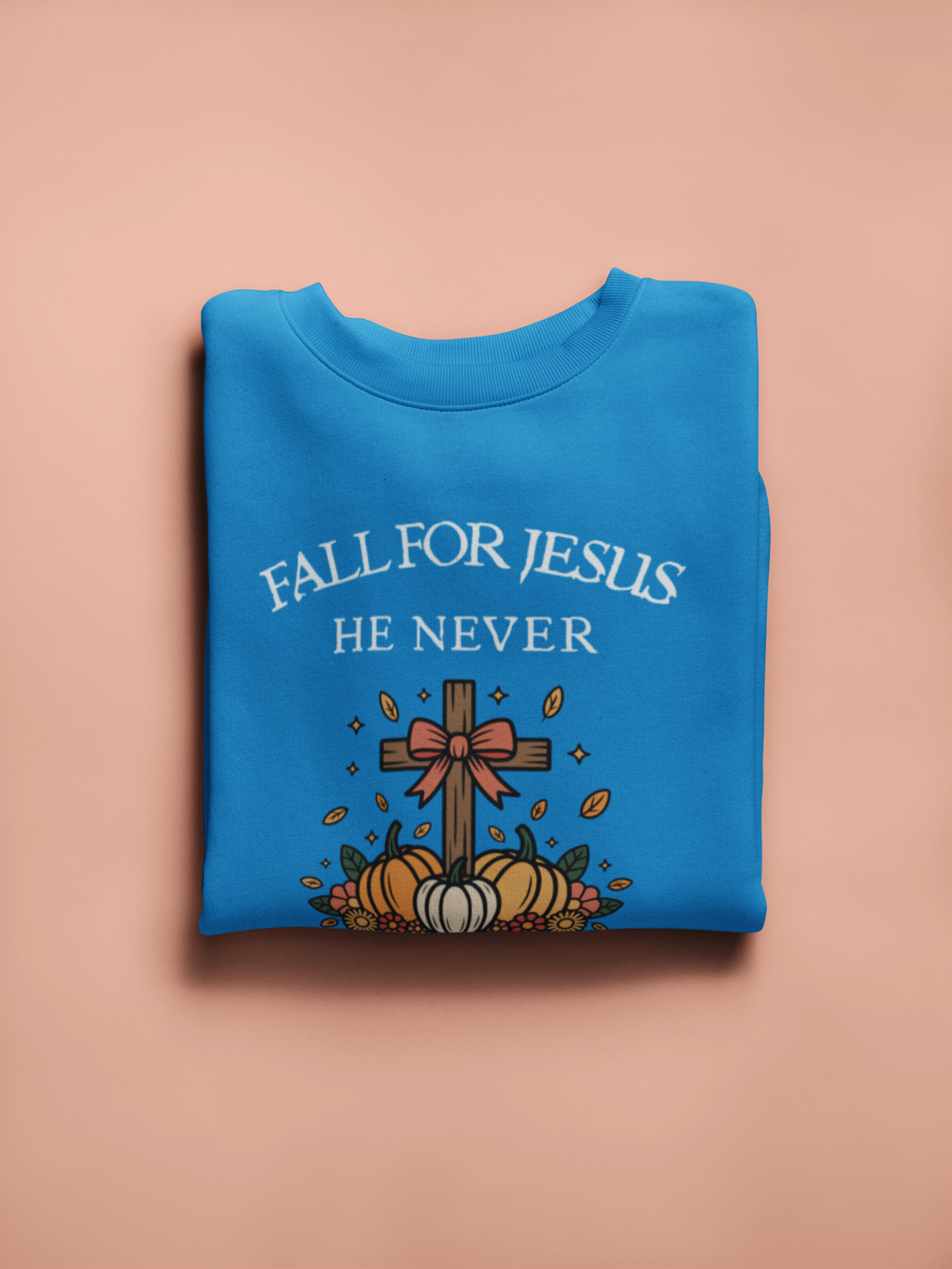 Blue sweatshirt with 'Fall for Jesus He Never' text and cross design on a beige background