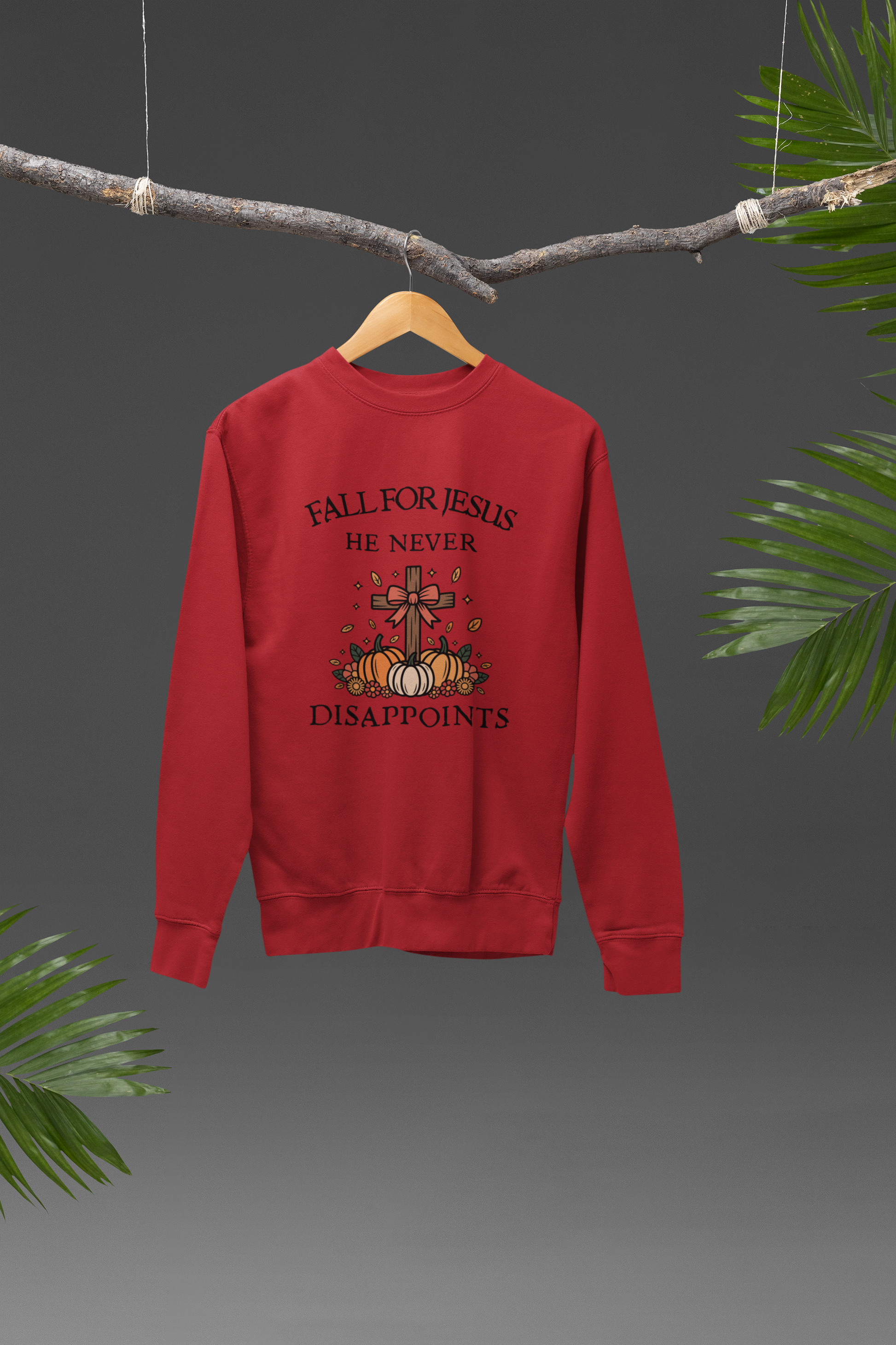 Red sweatshirt with text and graphics on a hanger against a dark background with green leaves.