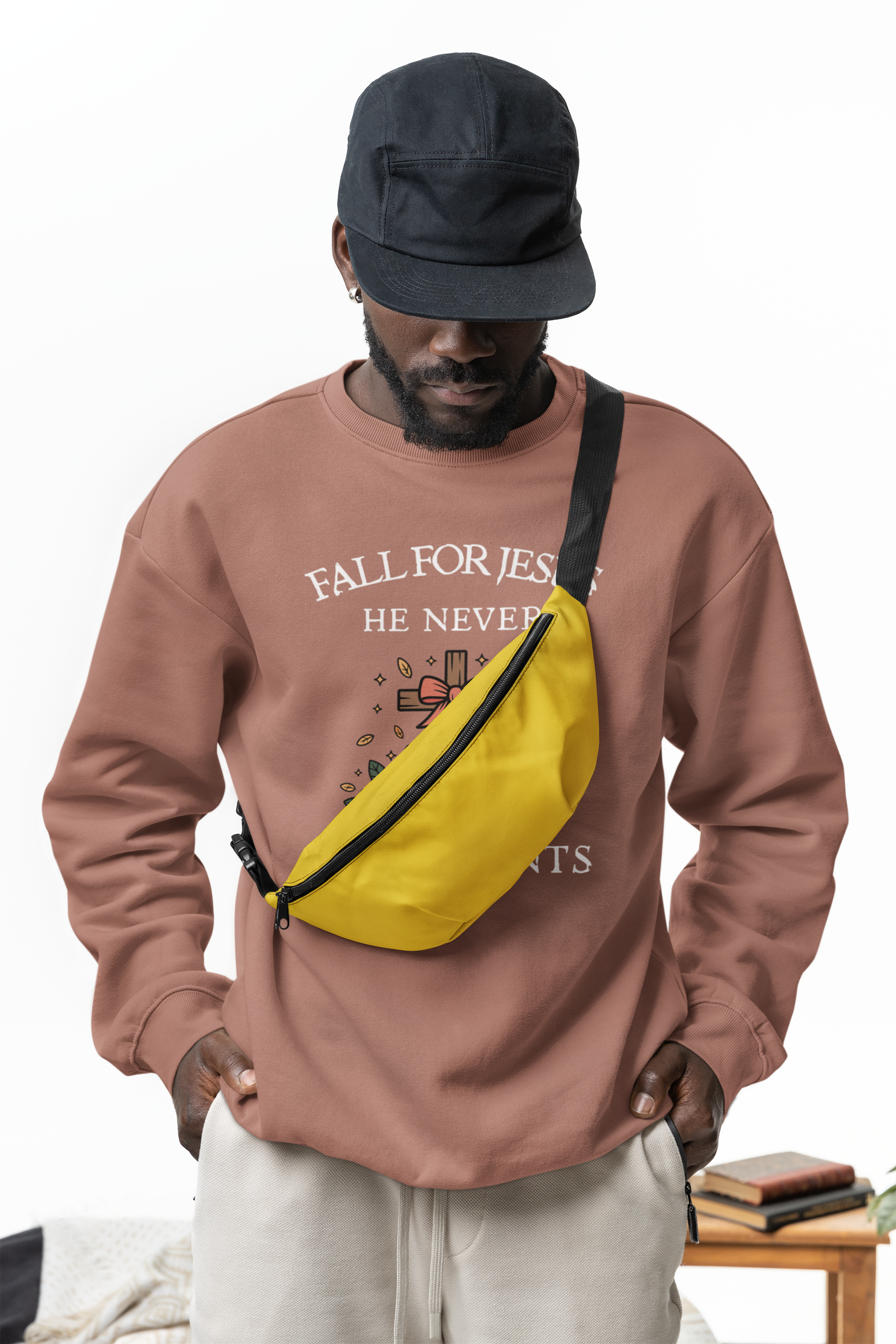 Person wearing a brown sweatshirt with text and a yellow fanny pack, standing against a white background.