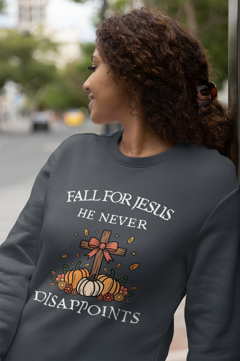 Person wearing a dark gray sweatshirt with a graphic and text, standing outdoors.