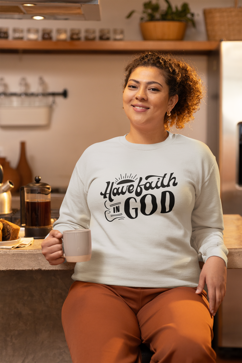 Person wearing a sweatshirt with 'Have faith in God' text in a kitchen setting
