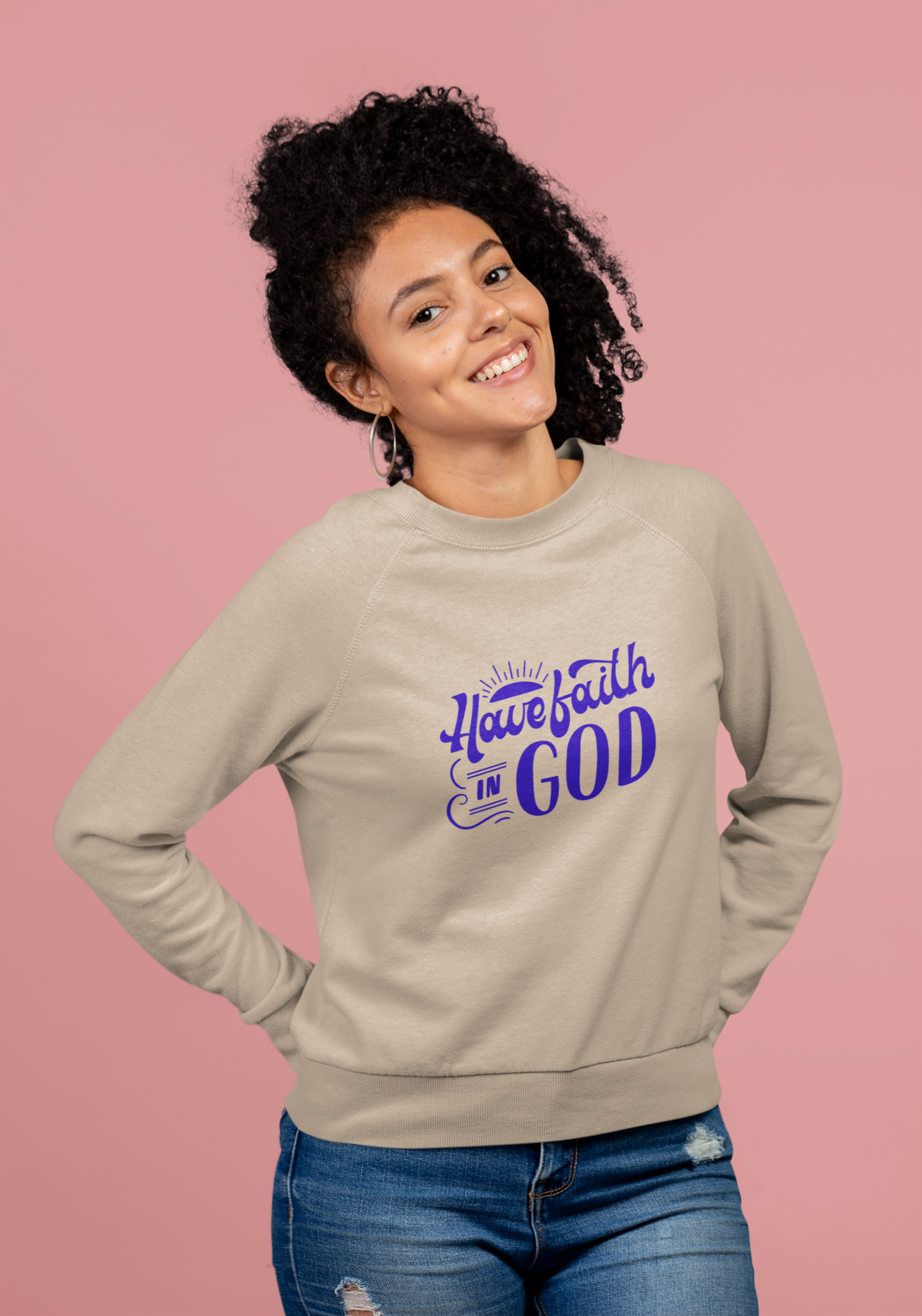 Woman wearing a beige sweatshirt with 'Have faith in God' text on a pink background