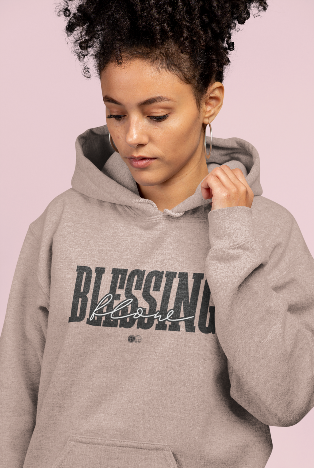 Person wearing a gray hoodie with 'Blessing' text on a pink background