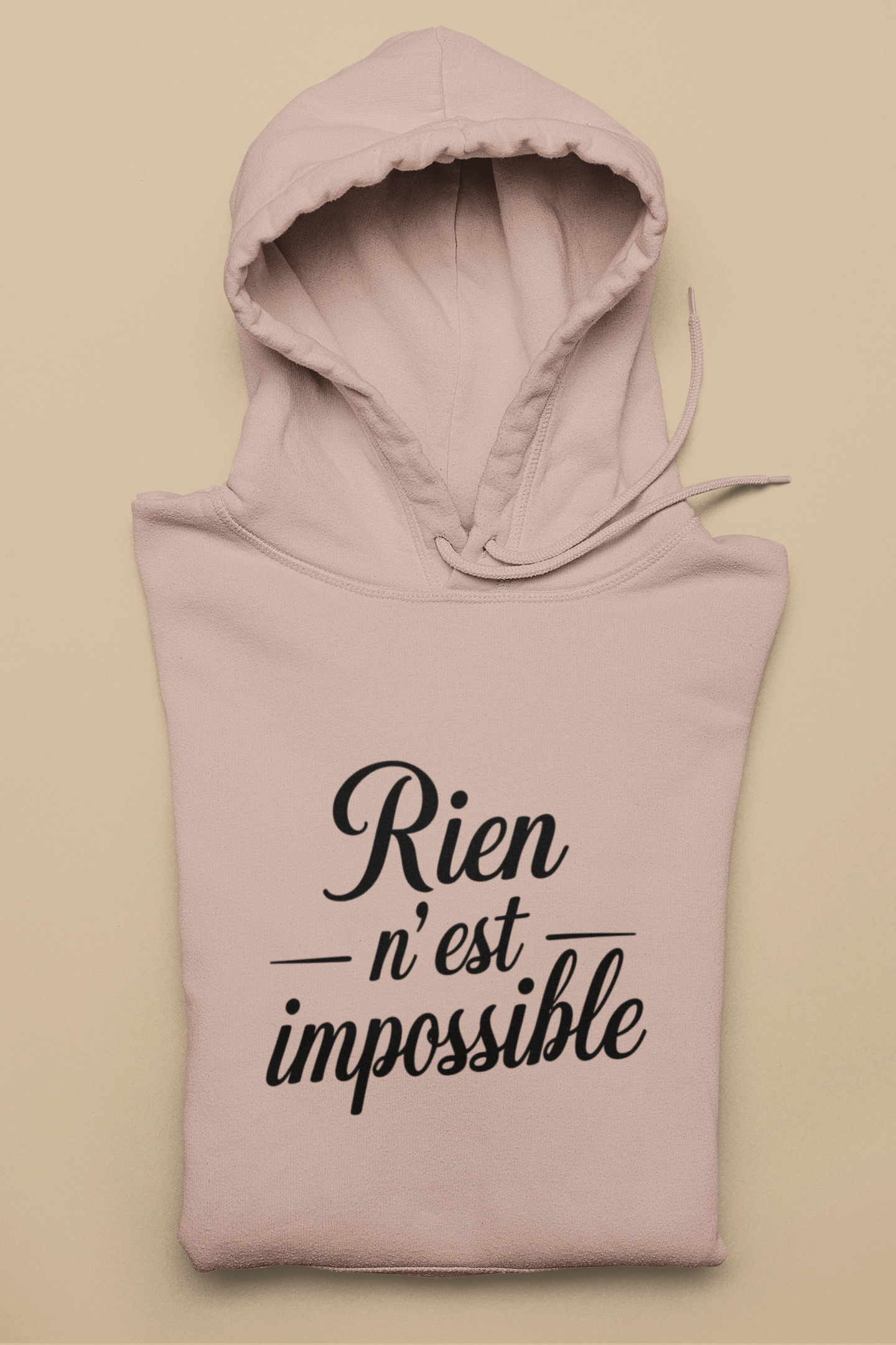 Pink hoodie with 'Rien n'est impossible' text on a beige background