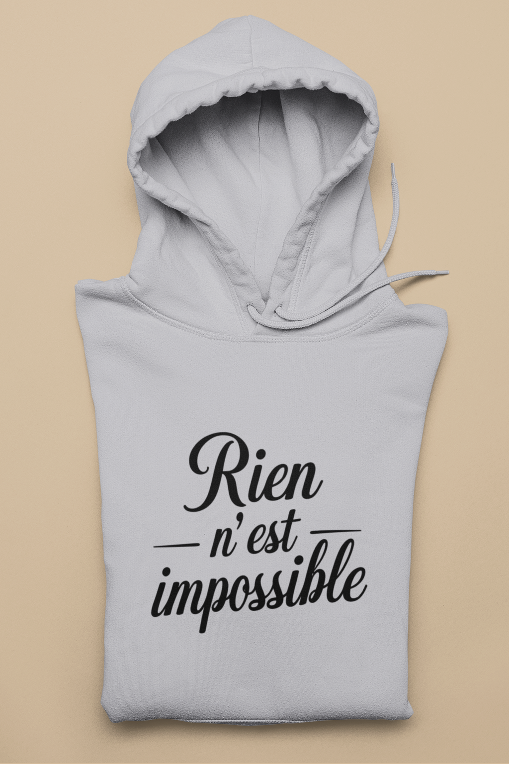 Gray hoodie with 'Rien n'est impossible' text on a beige background