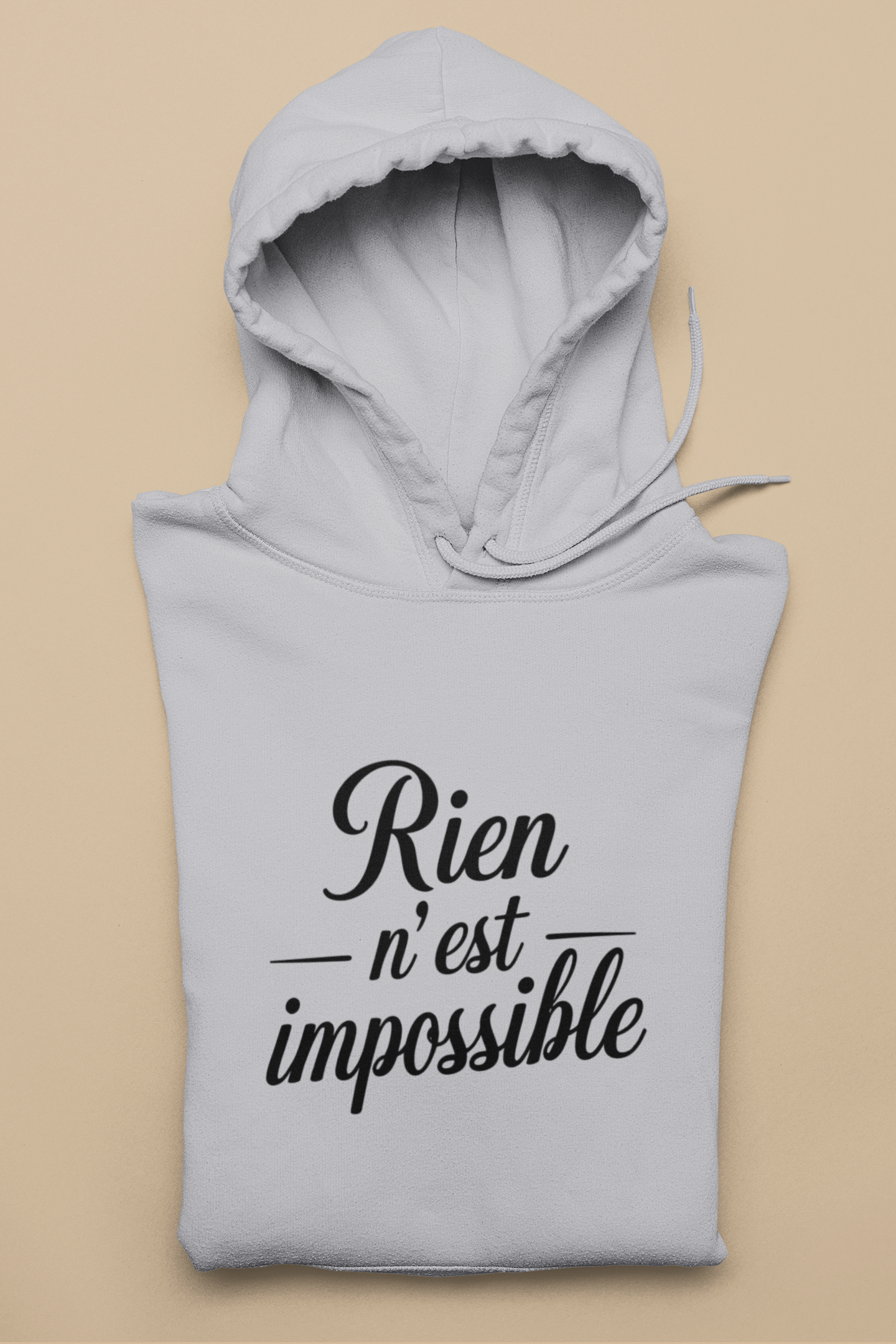 Gray hoodie with 'Rien n'est impossible' text on a beige background