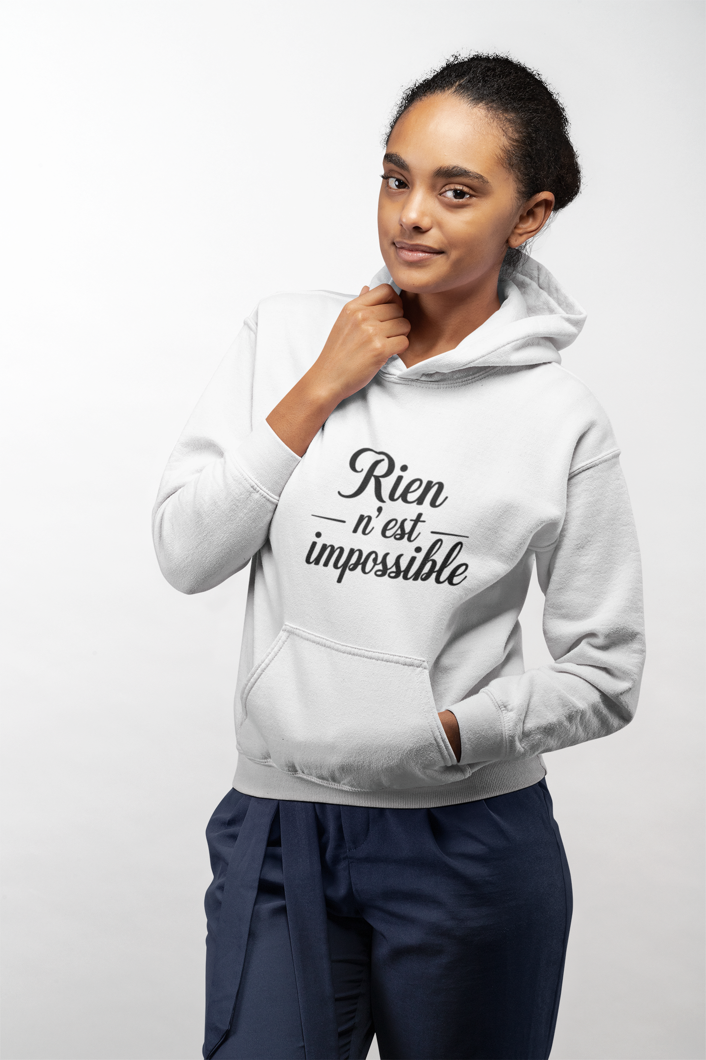 Woman wearing a white hoodie with 'Rien n'est impossible' text on a plain background