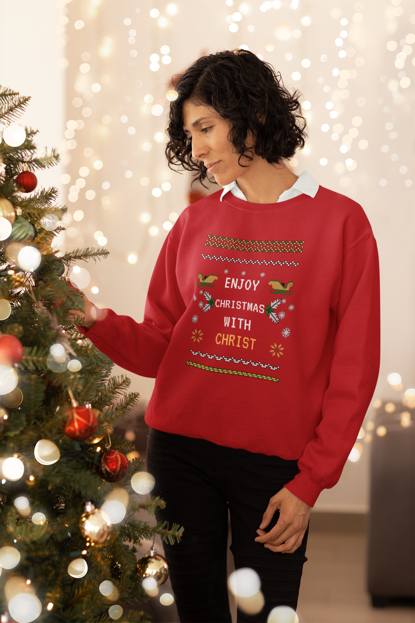 Person wearing a red Christmas sweater with festive design, standing next to a decorated Christmas tree.
