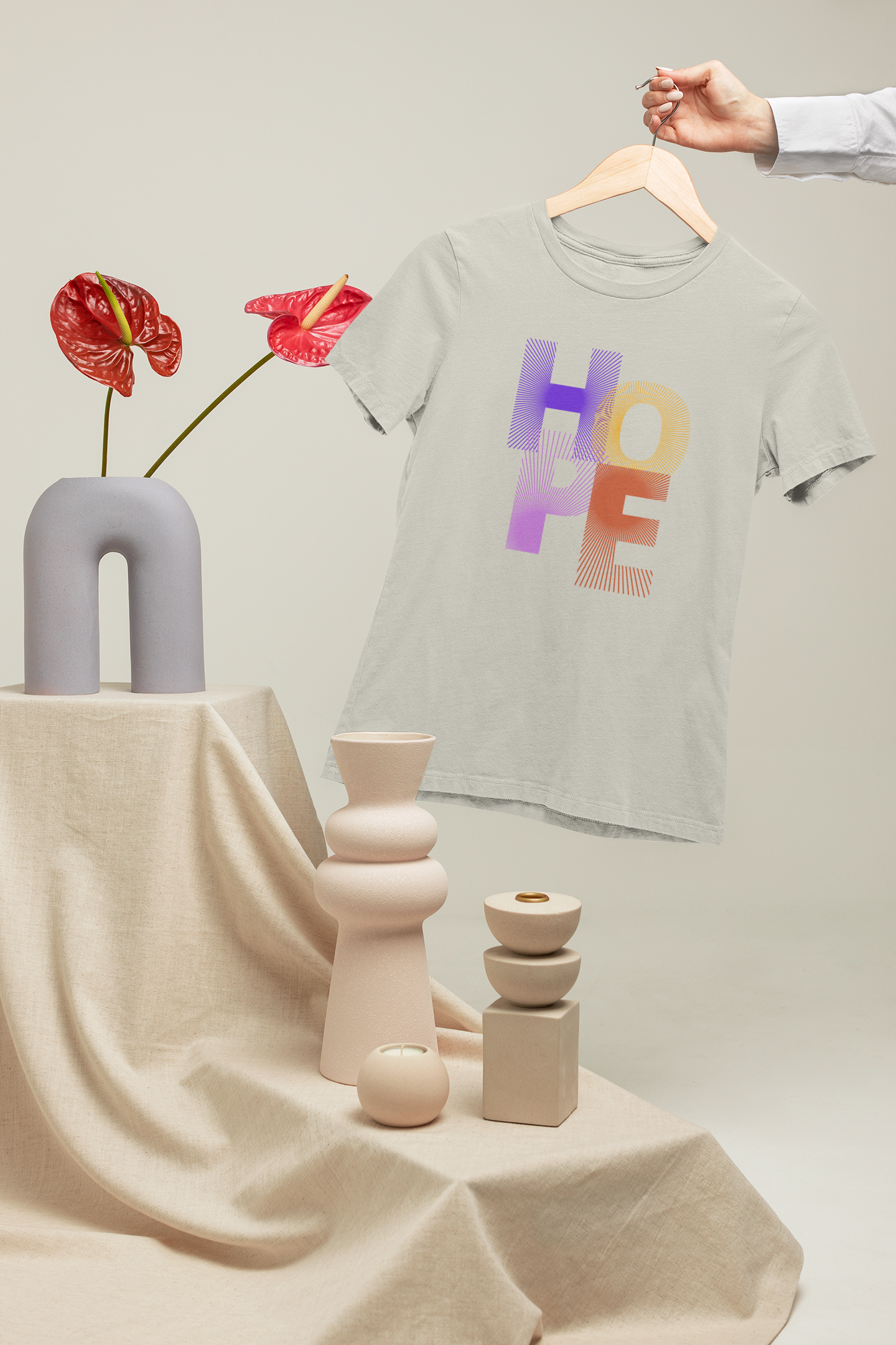 T-shirt with 'HOPE' printed on it hanging on a hanger next to decorative vases and flowers.