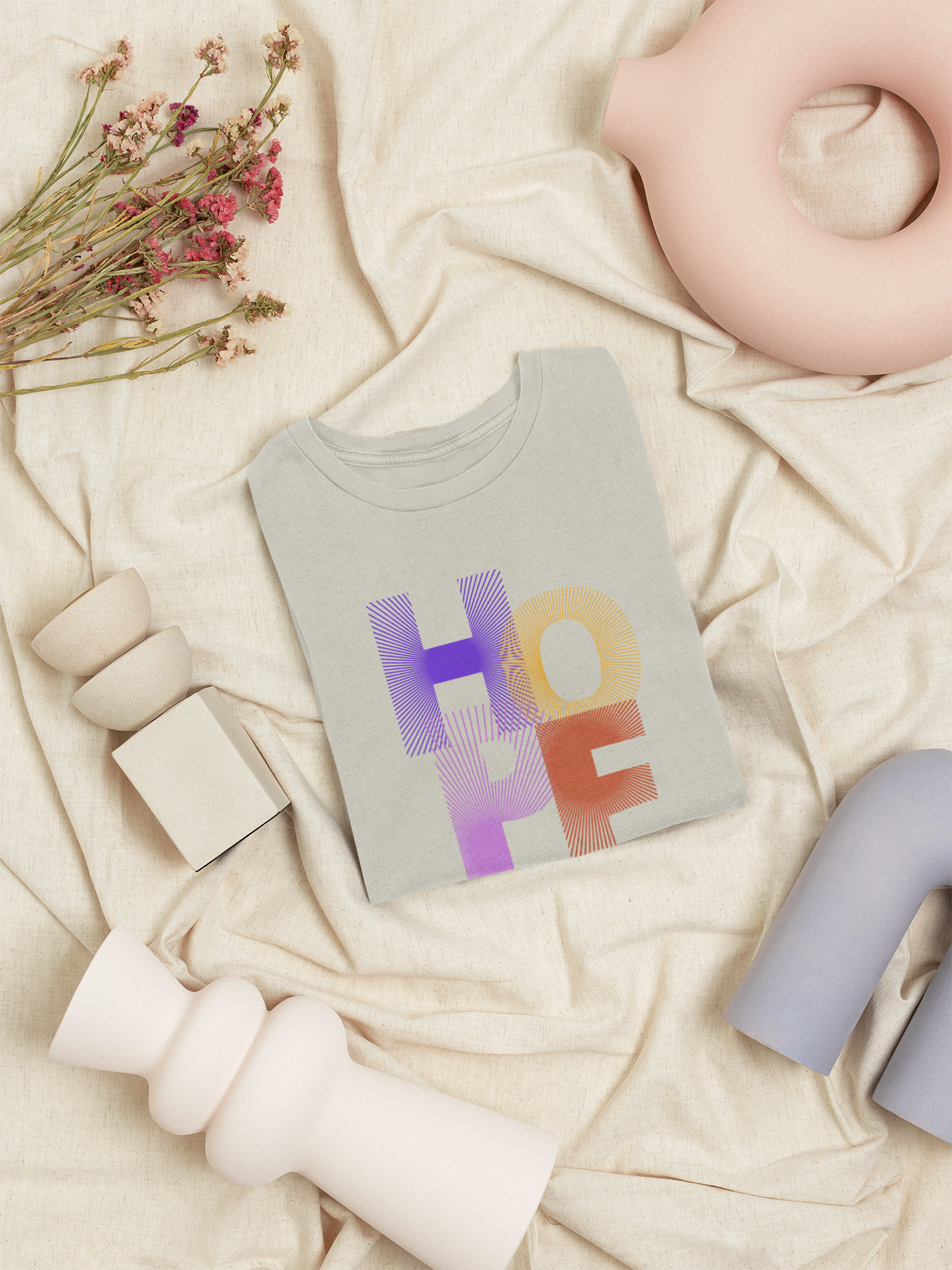 Gray t-shirt with 'HOPE' printed in colorful letters on a soft beige background.